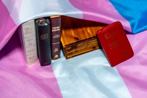 Several Bibles resting on a transgender flag