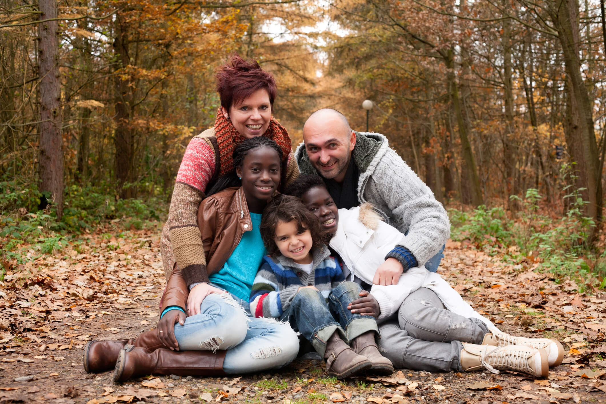 Multicultural family posing in the woods during autumn