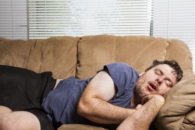 A man exhibiting sloth by sleeping on the couch