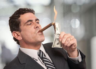 A man showing greed by lighting his cigar with money