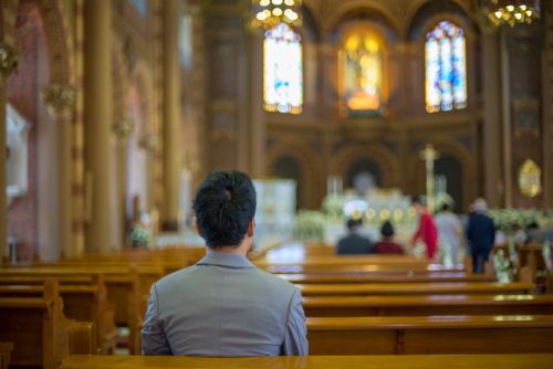 A man following doctrine by praying at church.