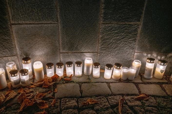 Memorial candles glowing beside a stone wall on All Saints' Day