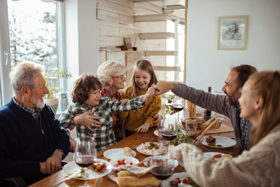 Multi-generational family sharing a meal together and celebrating around the dining table.