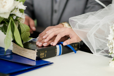 Bride and groom place their hands together on a Bible during a wedding ceremony.