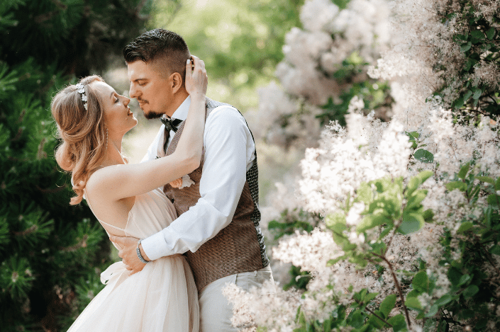 Bride and groom embracing beside flowering trees outdoors