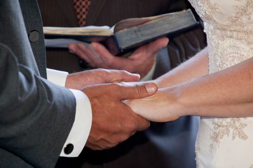 Minister Reading Script With Couple Holding Hands