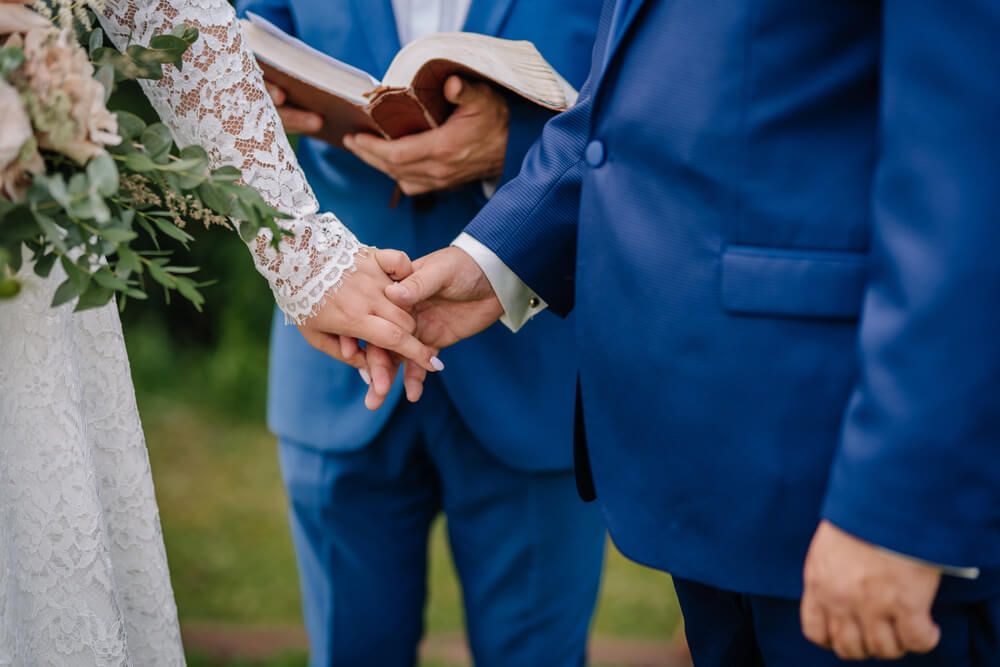 Officiant in front of couple with clasped hands