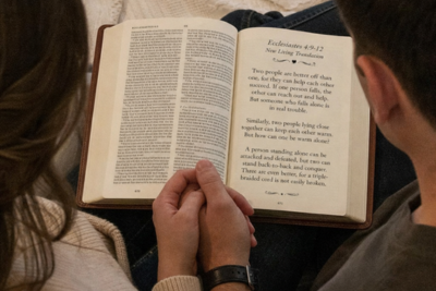 Couple holding hands while reading Ecclesiastes 4:9-12 about companionship and unity.