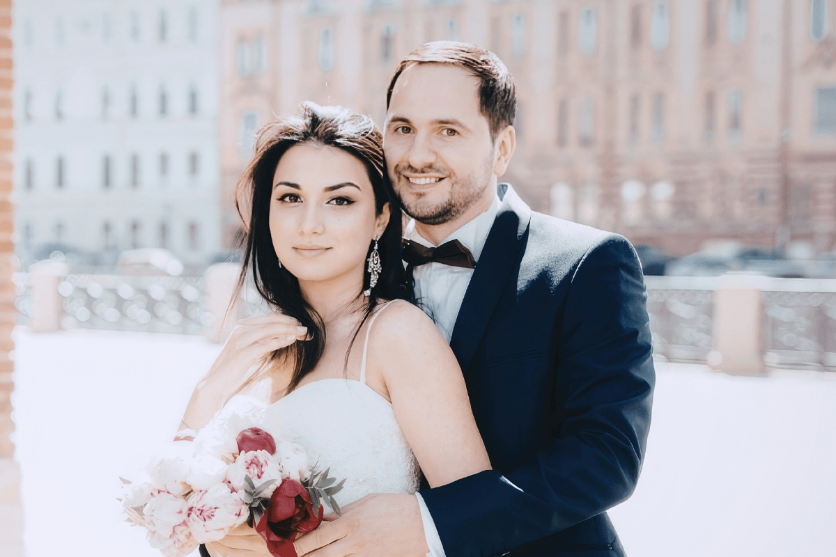 Newlywed couple poses together outdoors after their wedding ceremony.