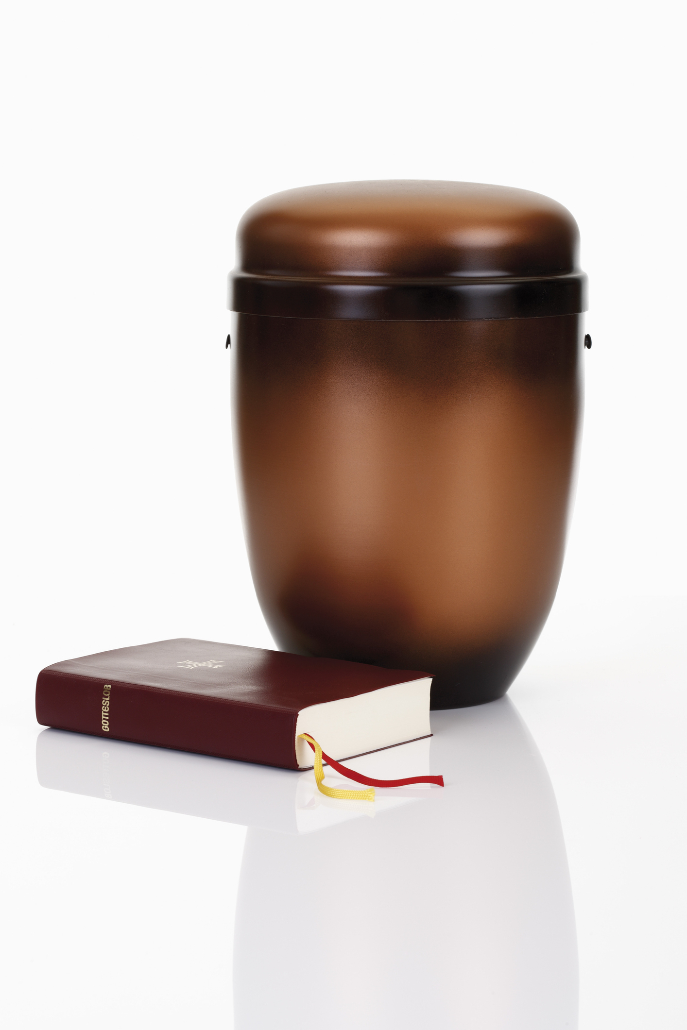An urn with cremated remains next to a bible.