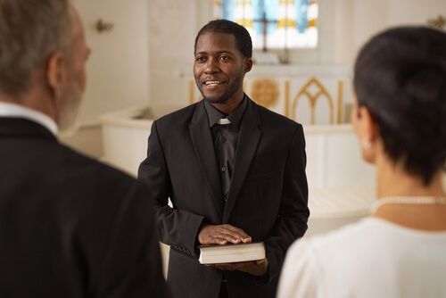 An officiant standing infront of a couple in a chapel in a different state