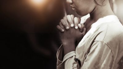 A woman of faith praying with hands folded
