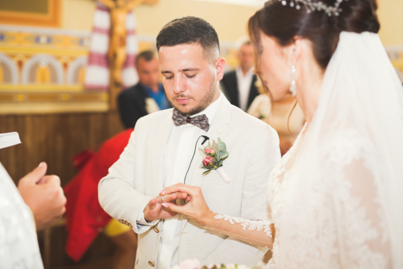 during-ceremony.jpg Groom places a wedding ring on the bride's finger during a wedding ceremony while the officiant leads the exchange of rings.