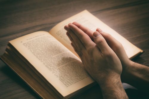 Hands in Prayer Over a Bible