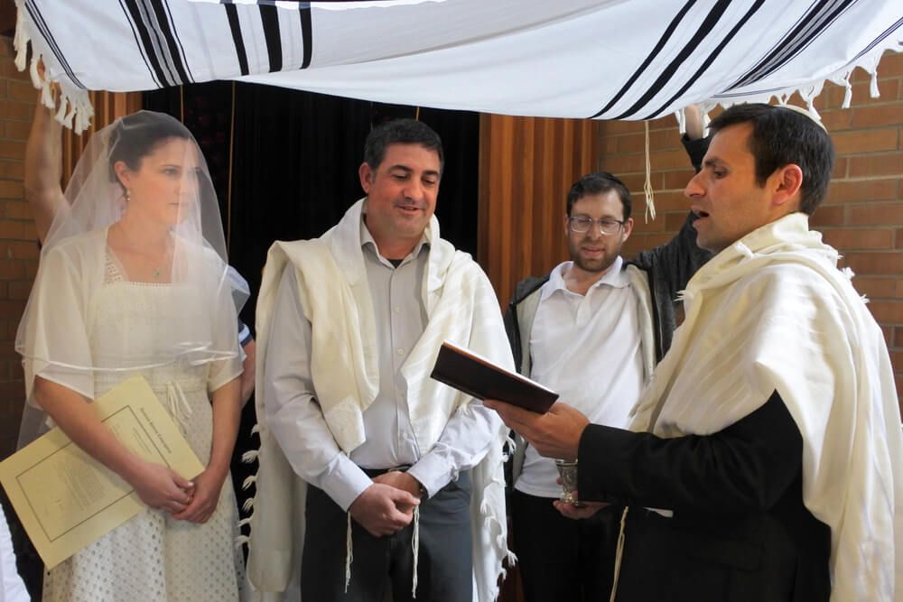 Jewish couple being married by rabbi