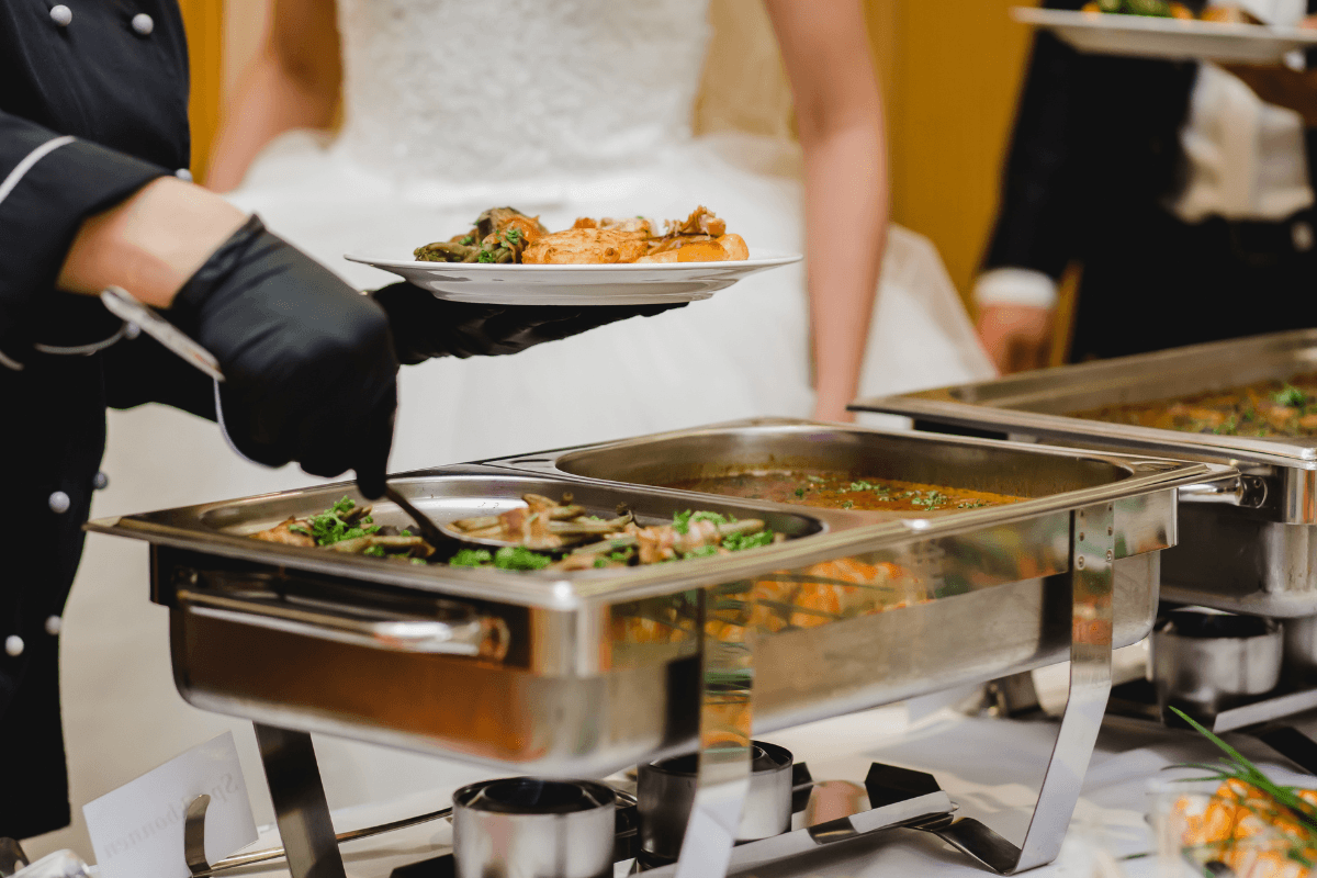 Caterer serves food from a buffet during a wedding reception.