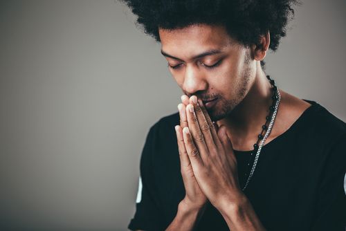 A person expressing forgiveness with their palms pressed together