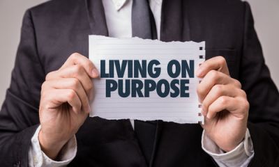 A man holding a small sign that says Living On Purpose