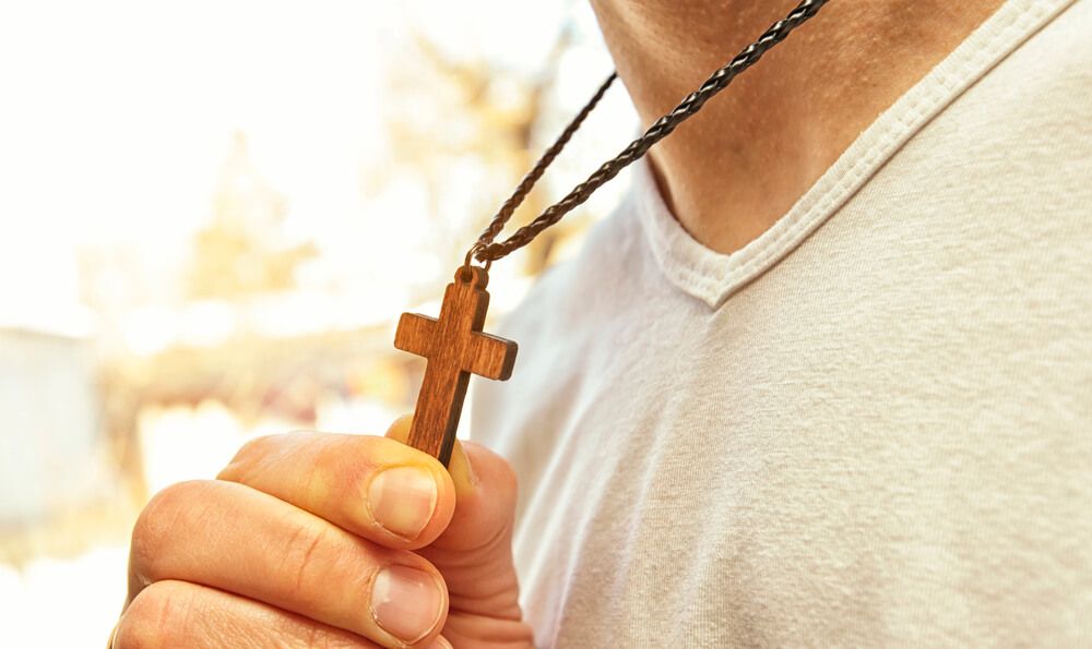 A man holding a cross necklace
