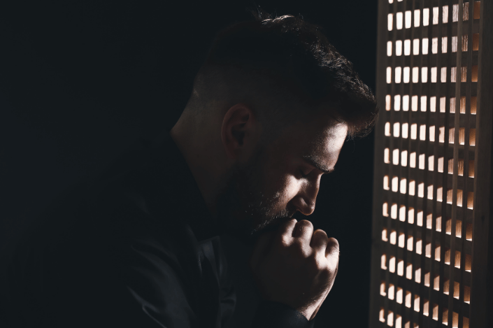 Man bowing his head with hands clasped in prayer