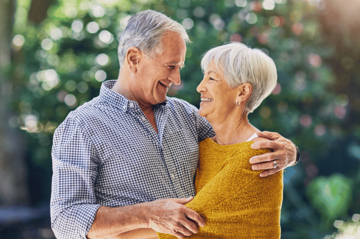 Older couple smiling and embracing outdoors, illustrating the love and commitment celebrated in a vow renewal.