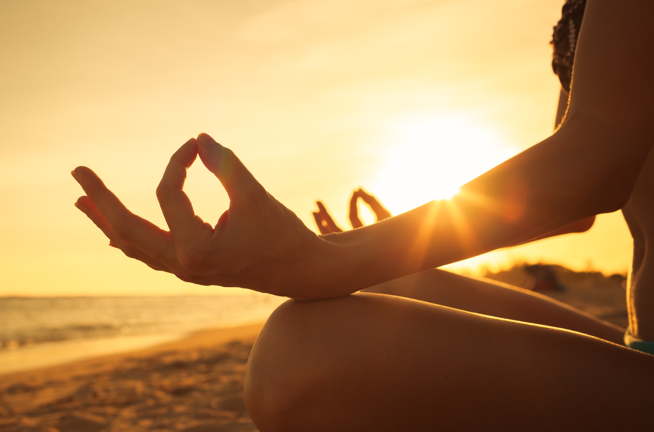 A woman practicing meditation on a beach. 