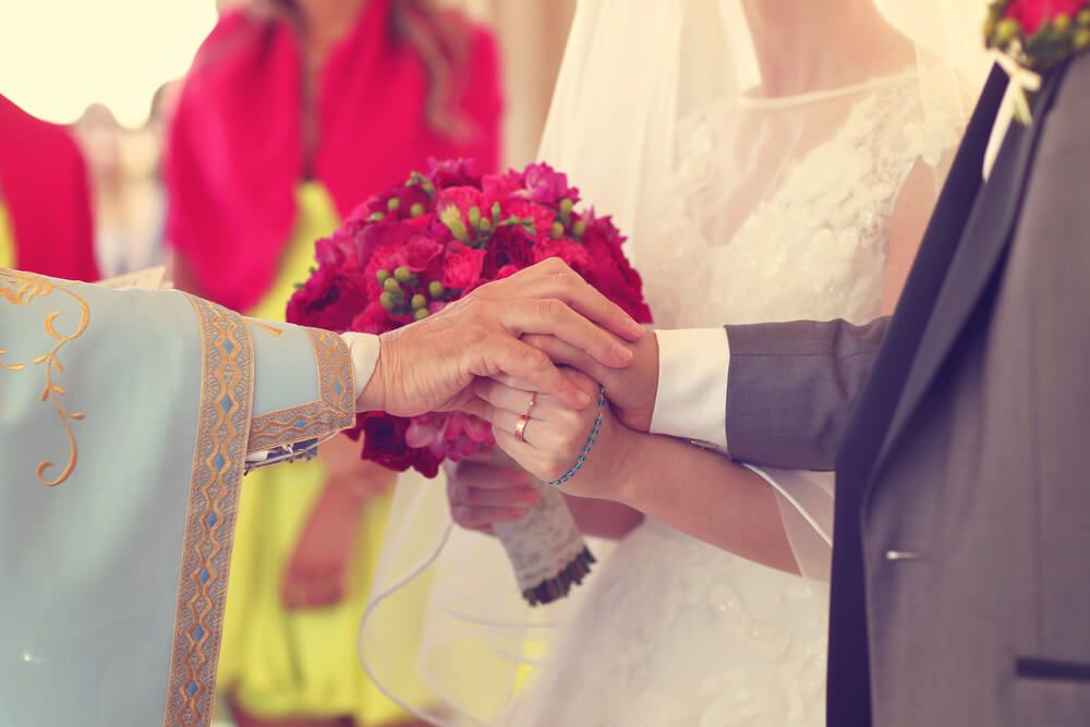 A couple and wedding officiant's hands being clasped.