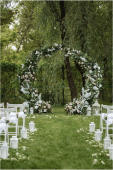Outdoor wedding ceremony space with white chairs and a floral arch