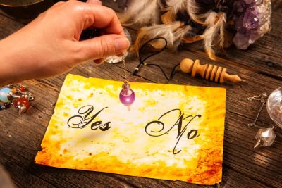 A divination pendulum held over a paper saying yes and no