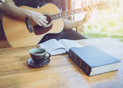 Person With a Bible Playing the Guitar