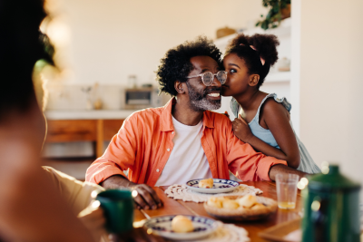 Daughter whispering to her father at the dinner table
