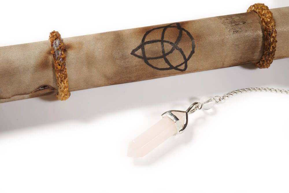 A scroll with a triquetra on it next to a crystal.
