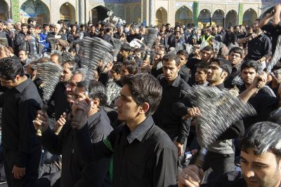 Shia Muslims participate in an Ashura mourning procession, performing ritual chest beating and chain mourning to commemorate Imam Hussain's martyrdom at Karbala.