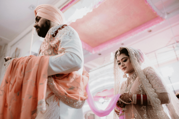 Sikh groom in a turban walking beside a bride in traditional wedding attire