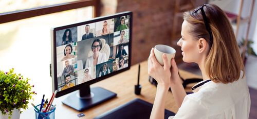 A woman drinking from a mug while sitting on an online video chat.