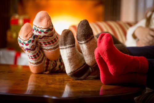 Three Pairs of Feet With Cozy Socks On Christmas Eve