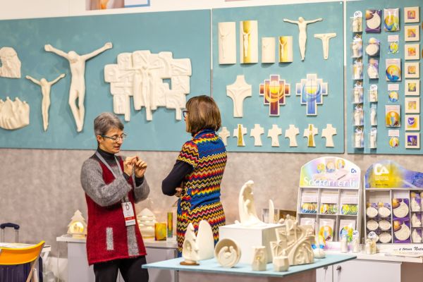 Two women at a church event discussing religious artwork on display.