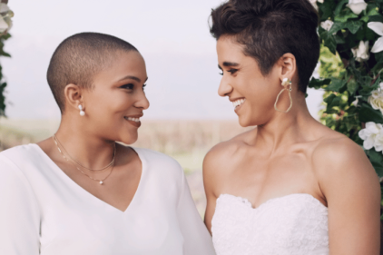 Two brides smiling at each other during their wedding