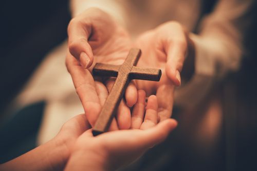 Minister Handing Off A Wooden Cross