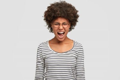 A woman expressing wrath standing in front of a white background