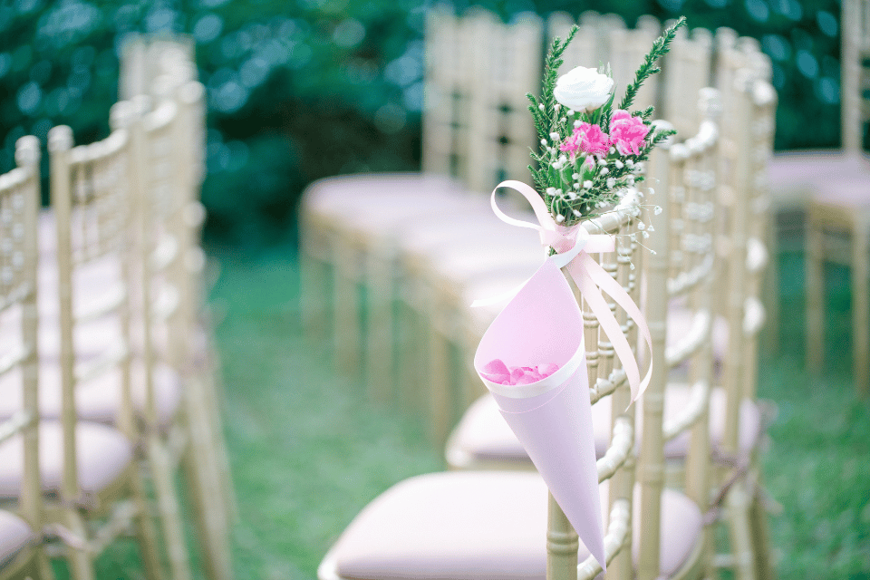 Floral memorial arrangement tied to a chair along an outdoor wedding aisle