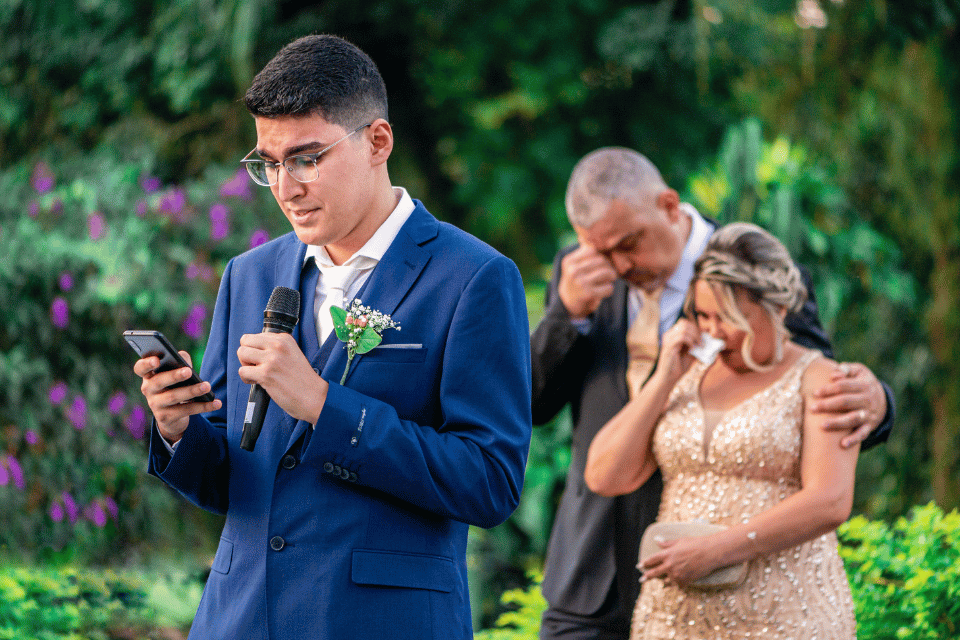 Wedding guest giving a memorial speech as an emotional couple listens behind him