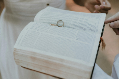 Two wedding rings resting on the pages of an open Bible during a wedding ceremony.