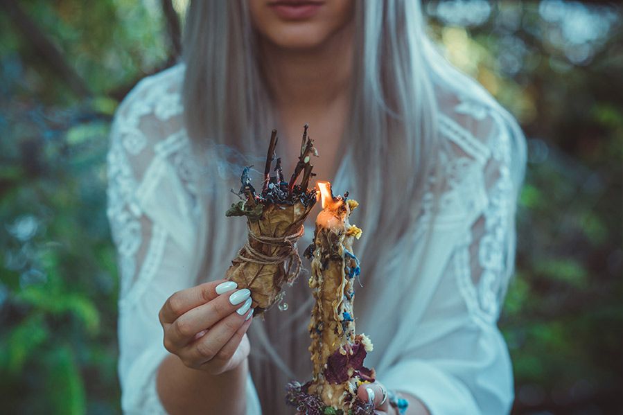 wiccan woman lighting sage with candle outdoors