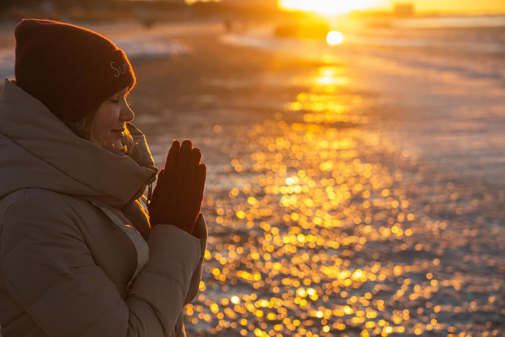 A woman praying at sunset during winter
