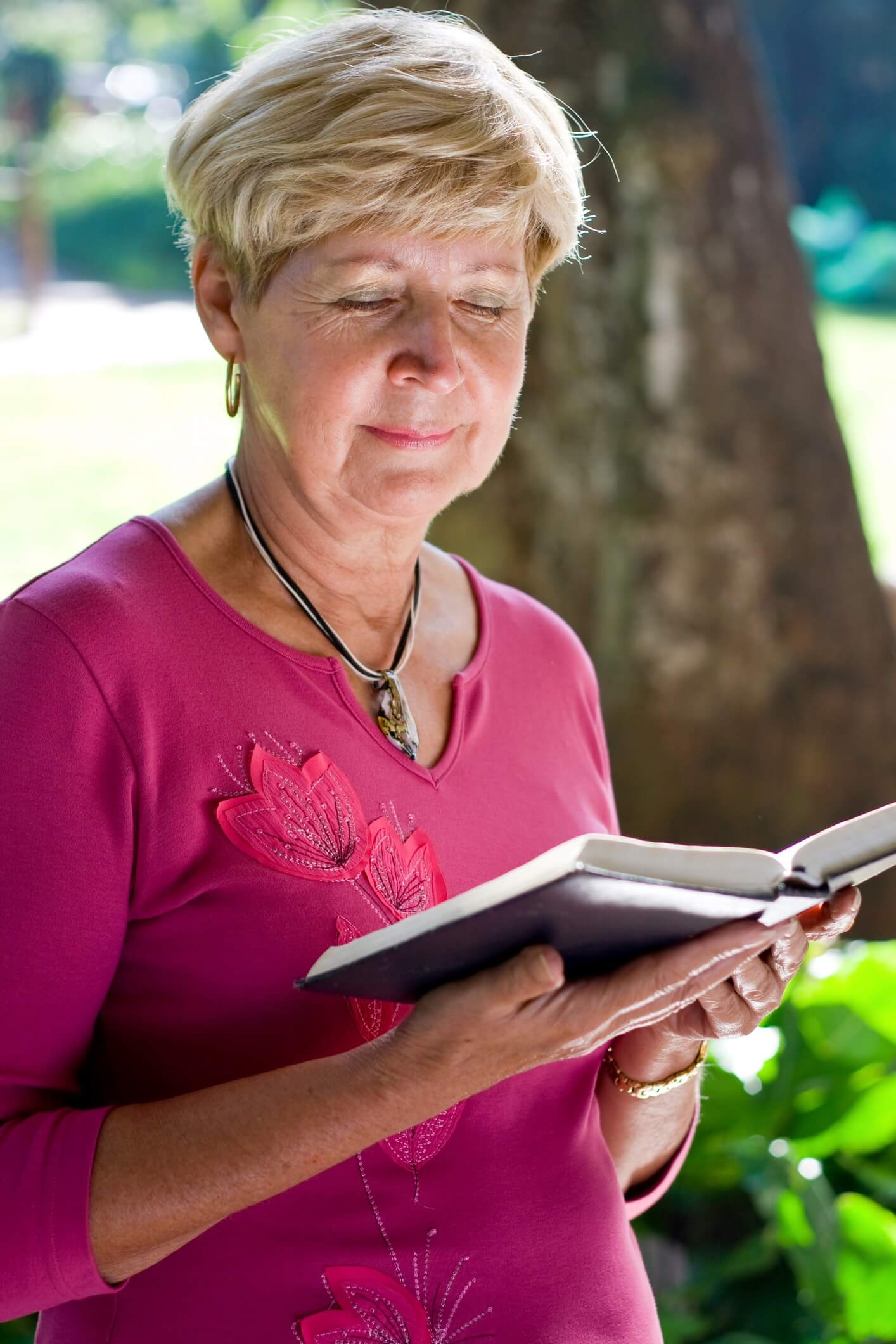 elderly woman reading a bible outdoors