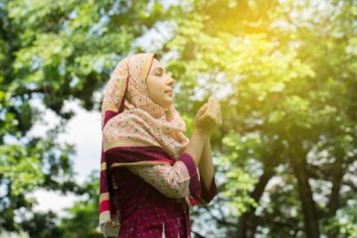 A young Muslim woman holding her hands together in prayer
