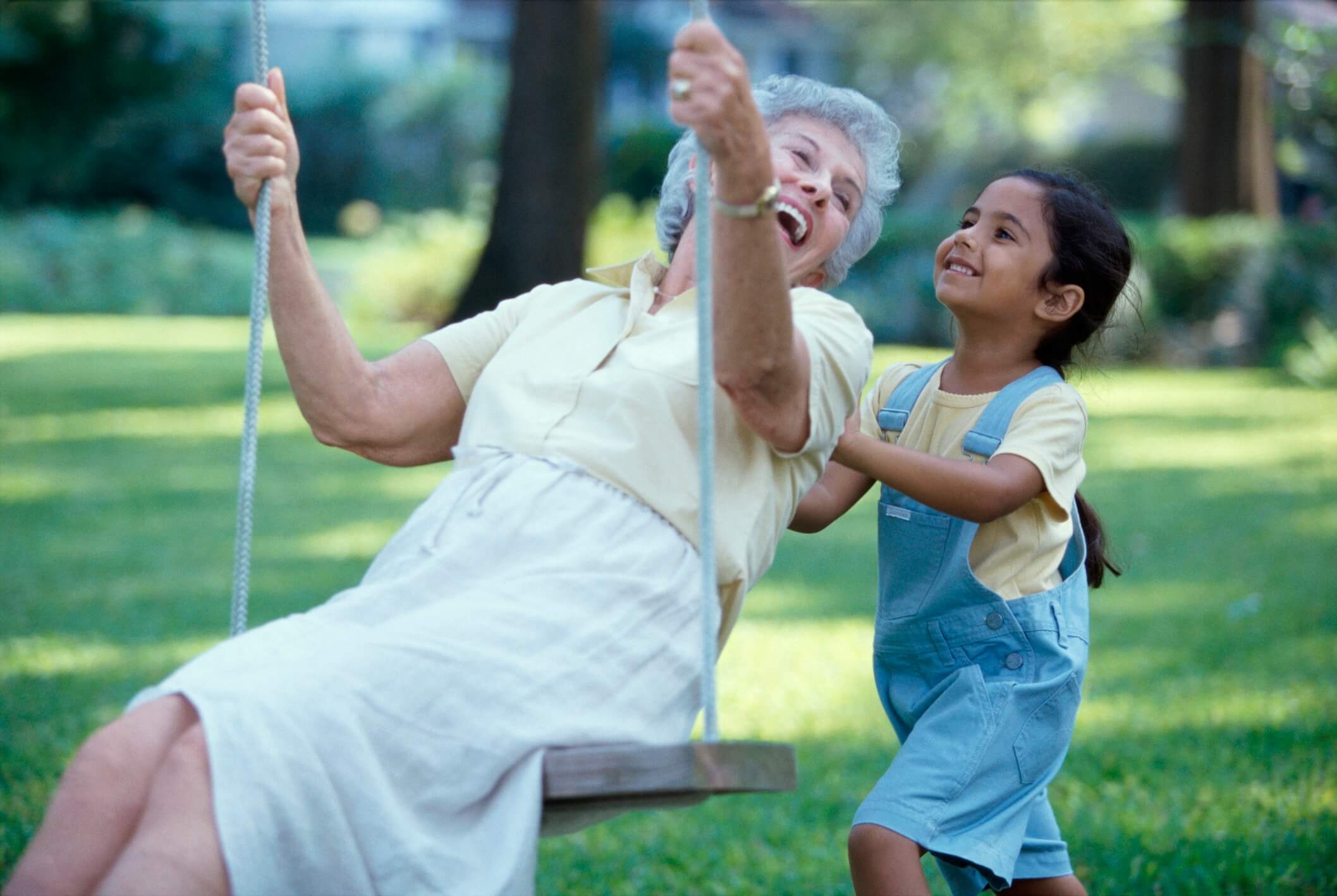 Side profile of a granddaughter pushing her grandmother on a swing