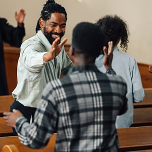 Two ministers extending hands to one another inside a church