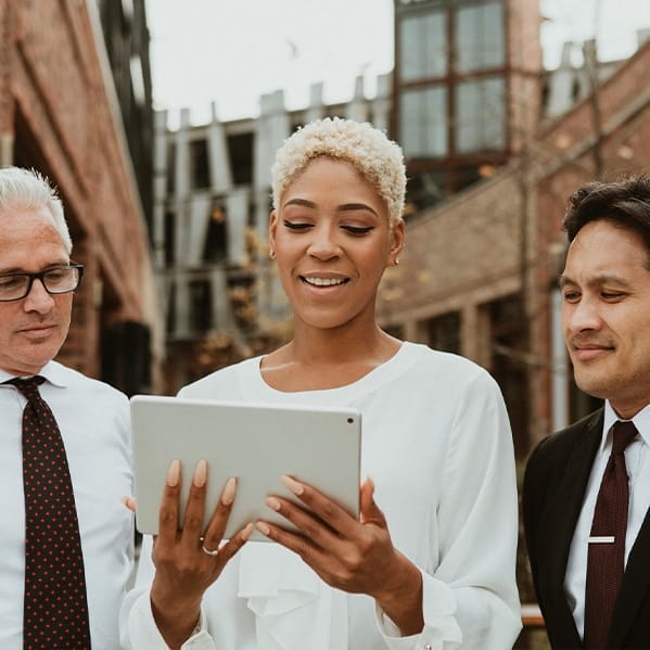 Woman reading from ipad with colleagues nearby